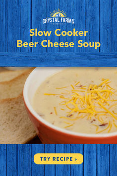 a bowl of beer cheese soup with crackers on the side and blue wooden background