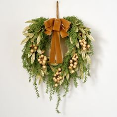 a wreath hanging on the wall with a bow and berries around it is decorated with greenery