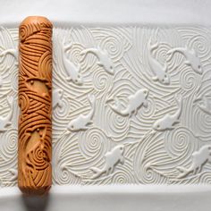 a carved piece of wood sitting on top of a white wall next to a pattern