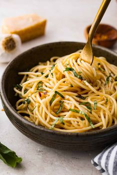 a bowl filled with pasta and parsley on top of a white tablecloth next to bread