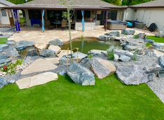 a backyard with large rocks and green grass