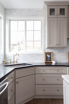 a kitchen with white cabinets and black counter tops