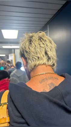 the back of a woman's head with a tattoo on her neck and shoulder