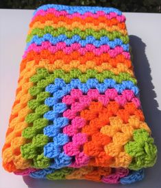 a multicolored crocheted dishcloth sitting on top of a white table