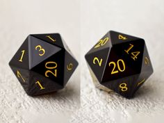 two black and gold dice sitting on top of a white cloth covered table next to each other