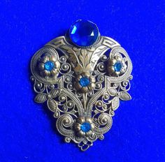 a blue and silver brooch sitting on top of a blue surface