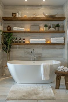 a white bath tub sitting in a bathroom next to a wooden shelf filled with towels