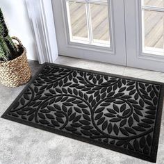 a black door mat sitting on top of a floor next to a potted plant