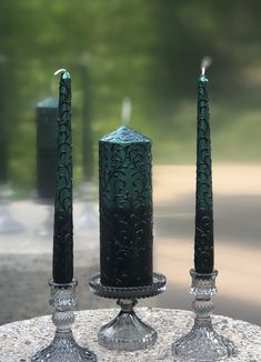 two green candles sitting on top of a table