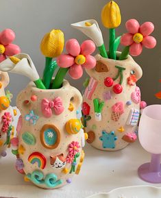 three ceramic vases with flowers in them on a table