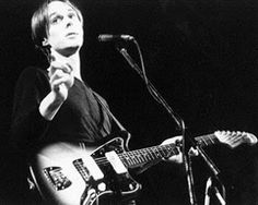 a woman holding a guitar while standing in front of a microphone