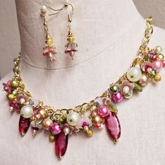 Make a statement with this one-of-a-kind floral charm necklace and earrings set. Gold wire wrapped freshwater pearls, glass pearls, cut Swarovski crystals, Czech glass flowers and leaves, gold plated findings, and assorted glass beads are hung on a gold-plated chain on the lower half of the necklace chain and finished with a matching lobster clasp.  This bright and colorful beaded necklace comes with all charms shown. Necklace length can be adjusted as requested, prior to checkout.  Matching floral earrings are hung on gold ear wires. Makes a great addition to your collection or a wonderful gift for someone special. Whimsical Dangle Jewelry With Lobster Clasp, Whimsical Pearl Charm Jewelry For Gifts, Whimsical Pearl Charm Jewelry As Gift, Pink Beaded Czech Glass Jewelry, Czech Glass Dangle Jewelry For Party, Whimsical Handmade Pearl Jewelry, Handmade Pink Czech Glass Jewelry, Pink Pearl Charm Jewelry For Wedding, Pink Beaded Crystal Jewelry