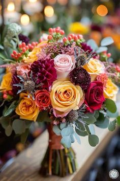 a bouquet of flowers sitting on top of a wooden table in front of some lights