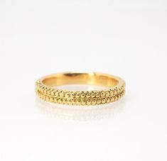 This is cast from a granulated original and is pictured in 14k yellow gold, but I can also cast this in Sterling or 18k yellow. Or would be happy to make a similar design for you in original 18k granulation!Granulation is a controlled fusing process that has been utilized for thousands of years. This unique surface will get more interesting with wear. The granules are individually placed and fused with a mouth torch. I then make a mold of the ring and pull a wax copy from that mold and cast it u Hand Forged Yellow Gold Round Band, 14k Yellow Gold Hammered Jewelry, Yellow Gold Nugget Brass Jewelry, 14k Stamped Yellow Gold Nugget Jewelry, Hammered 14k Yellow Gold Jewelry, Heirloom 14k Gold Jewelry, Heirloom Hand Forged Yellow Gold Jewelry, Classic 22k Gold Ceremonial Jewelry, Ceremonial 14k Gold Jewelry With Diamond Cut