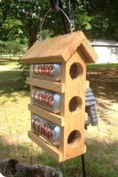 a bird house made out of wood with cans hanging from it's roof and two birds in the background