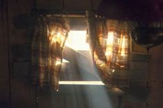 the sun is shining through the window in the room with the curtain open and light coming from behind it