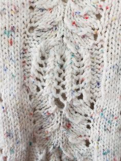 a white knitted sweater with multicolored details on the shoulders and back, close up