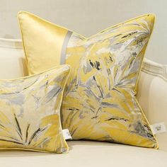 two yellow pillows sitting on top of a white couch