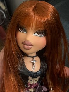 a close up of a doll with red hair and cross on it's chest