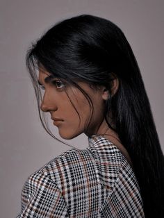 a woman with long black hair wearing a blue and white checkered shirt looking off to the side