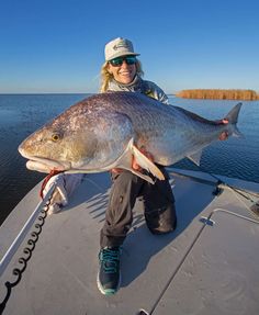 a woman on a boat holding a large fish