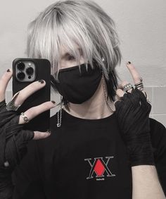 a person with grey hair wearing a black mask and holding up a cell phone