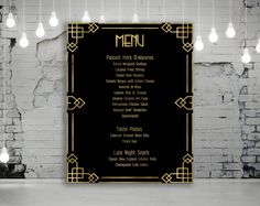 a black menu with gold trim on a white brick wall and chandelier hanging from the ceiling