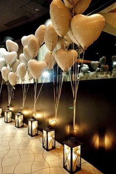 many white heart shaped balloons are hanging from the ceiling in front of candles and lanterns