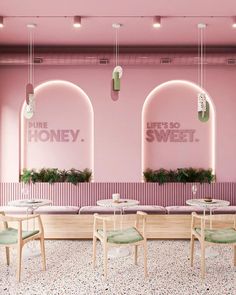 the interior of a restaurant with pink walls and wooden tables, green chairs and planters