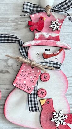 a snowman ornament hanging on the side of a wooden wall with two birds