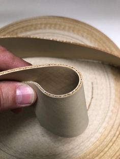 a person is holding a piece of paper on top of a straw hat that's folded in half