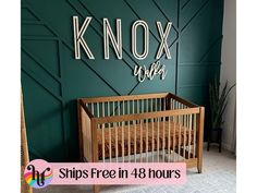 a baby crib in front of a green wall with the words knox over it