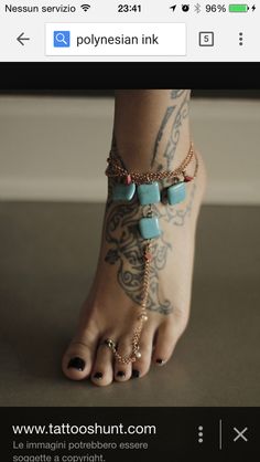 a woman's foot with tattoos on it and beads hanging from the ankle bracelet