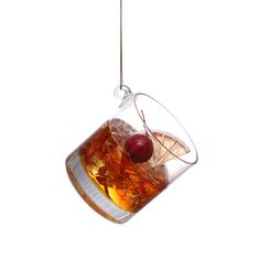 a glass filled with ice and two cherries hanging from it's side on a string