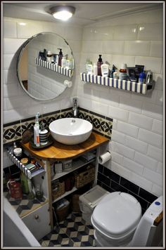 a bathroom with a sink, mirror and toilet in it's corner area next to a tiled wall