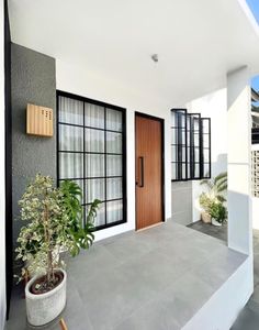 a house with two doors and some plants on the front porch, next to it is a potted plant