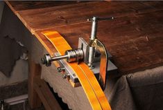 a wooden table topped with a metal clamp