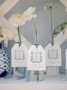 three vases with white flowers in them on a shelf next to a blue and white vase