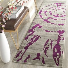 a purple and gray area rug in a living room next to a vase with flowers