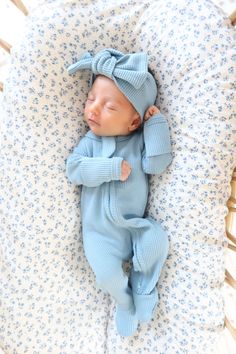 a baby sleeping in a crib wearing a blue outfit