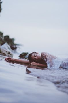 a woman laying on top of a body of water