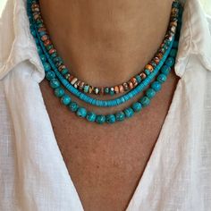 a woman wearing a white shirt and blue beaded necklace with turquoise beads on it