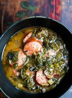 a bowl filled with meat and greens on top of a table