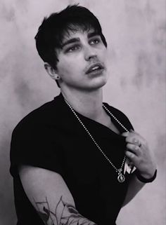 a young man with tattoos on his arm and chest is posing for a black and white photo