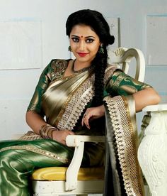 a woman sitting on top of a white chair wearing a green and gold sari