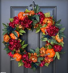 a wreath with flowers and pumpkins on the front door