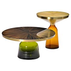 two round tables with different colored bases on each side and one green vase in the middle