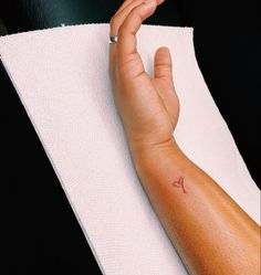 a person's arm with a small tattoo on it, resting on a towel