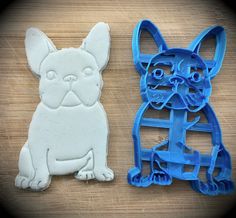 two cookie cutters shaped like dogs sitting next to each other on a wooden surface