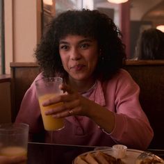 a woman sitting at a table with a glass of orange juice